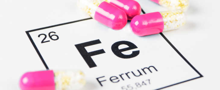 Pills with mineral Fe (Ferrum) on a white background with an inscription from the chemical table