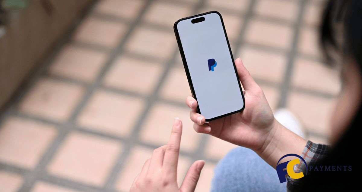 A person using a laptop to access their PayPal account and view the disadvantages of a PayPal business account